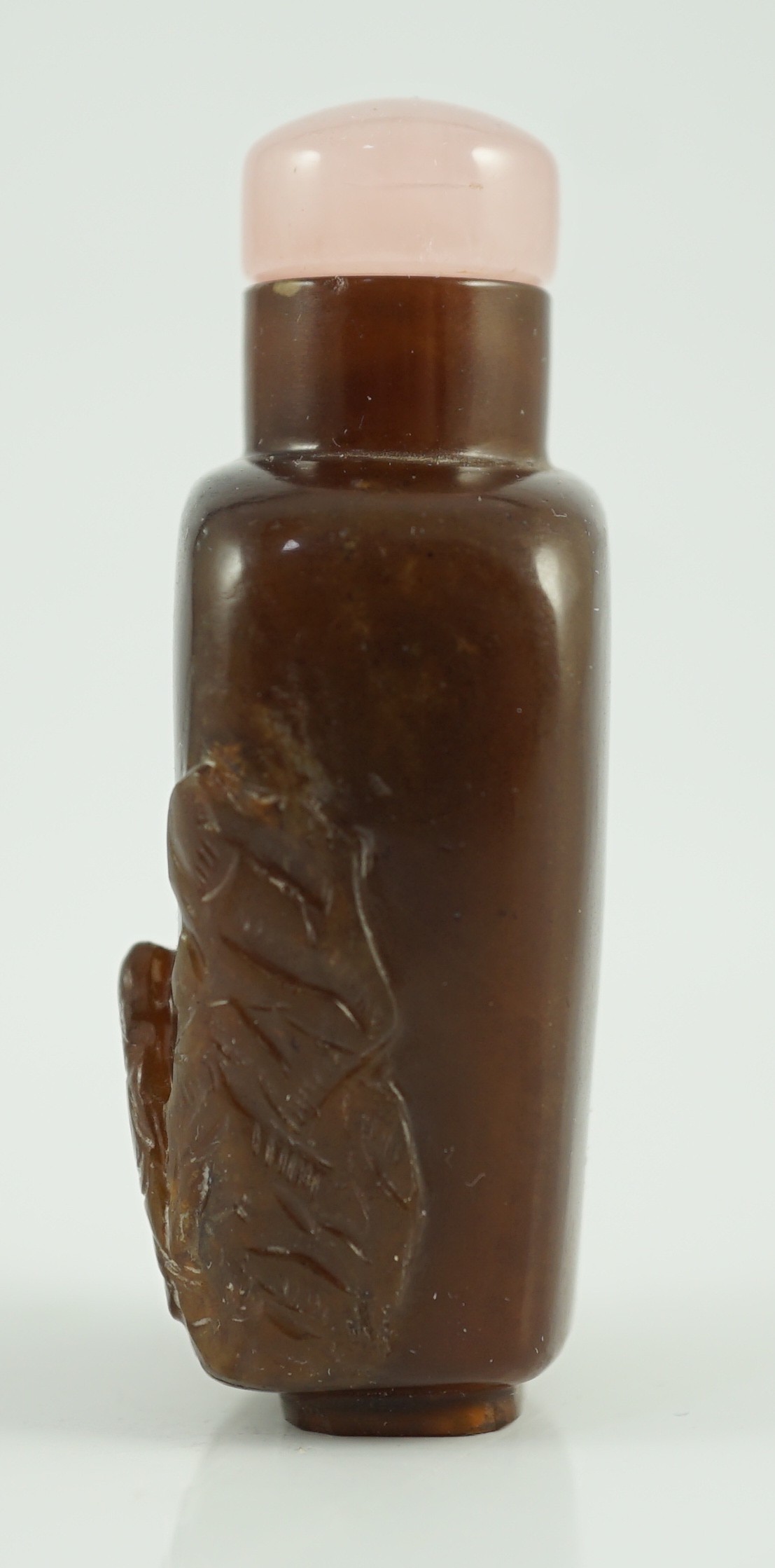 A Chinese brown jasper ‘sage’ snuff bottle, 19th century, carved in high relief with the figure of a boy seated holding an iron crutch amid rocks, before a gourd emanating the spirit of Li Tieguai, 5.8cm